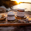 Jar of Healing Balm on a wooden tray outside with some supporting ingredients like Tallow