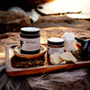 Jar of Mag Relief on a wooden tray outside with some supporting ingredients like Tallow and Frankincense Resin